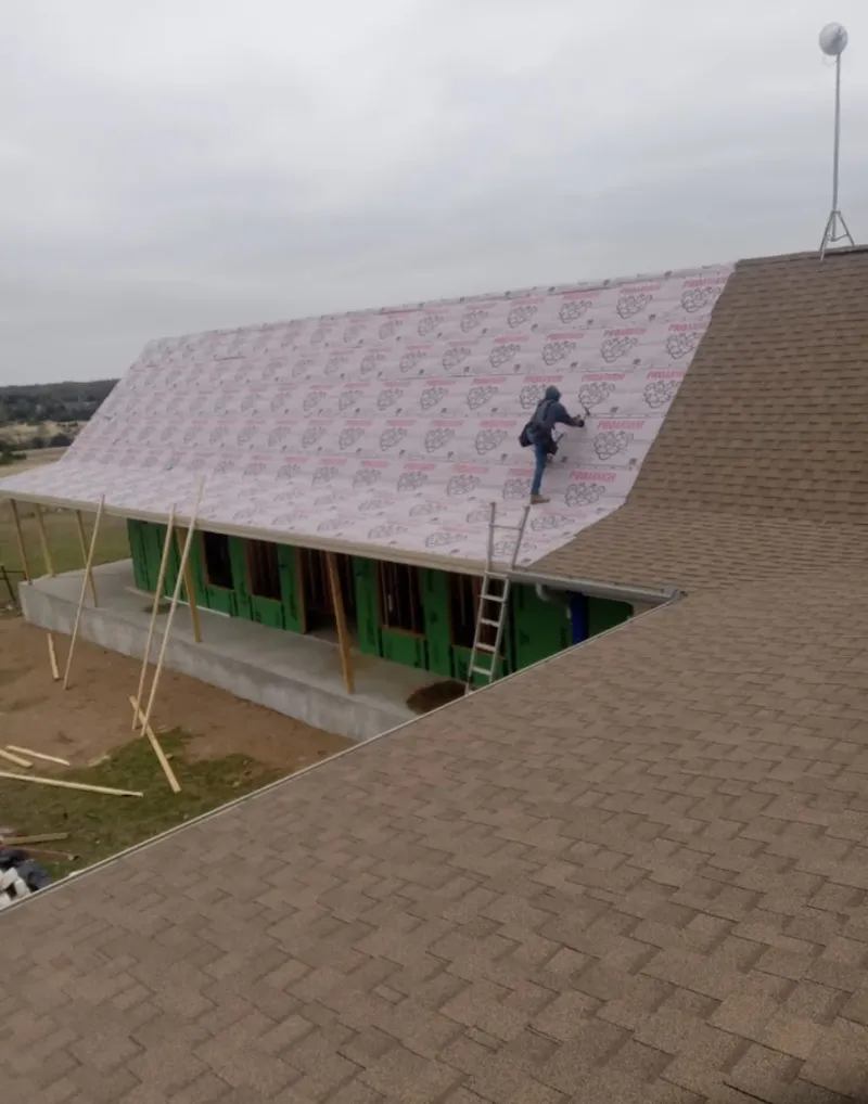 Worker preparing underlayment for a metal roof installation in Yulee